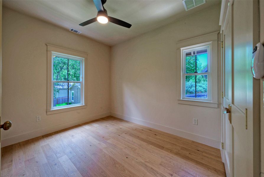 Bedroom #3. Hardwood floors and bright windows create a cheerful ambiance in this accommodating room.