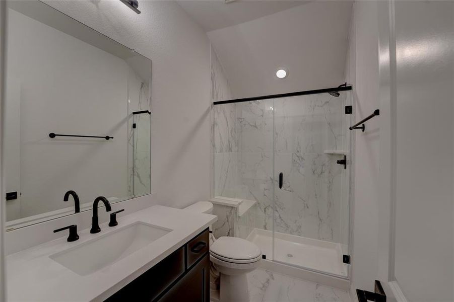 Full bath with marble finish floor, vanity, a marble finish shower, and toilet