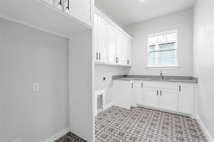 Washroom featuring hookup for an electric dryer, sink, light tile flooring, and cabinets