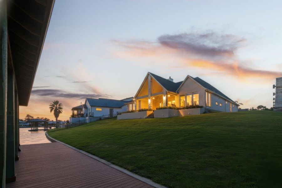 The home glows at sunset, showcasing its inviting architecture and outdoor lighting. Perfect for evening gatherings or simply enjoying the peaceful neighborhood ambiance.