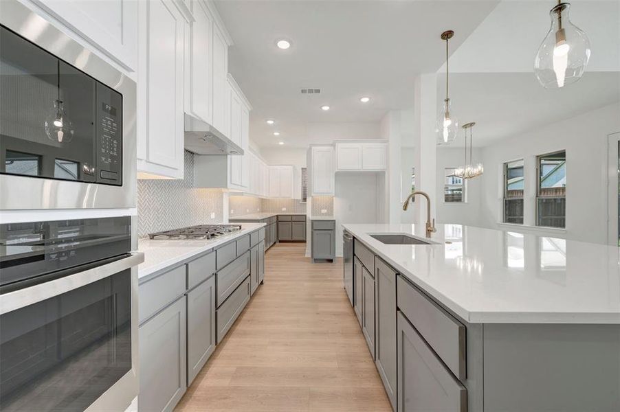 Contemporary kitchen featuring light wood-finish flooring, white upper cabinetry, and contrasting gray lower cabinetry Contemporary kitchen featuring light wood-finish flooring, white upper cabinetry, and contrasting gray lower cabinetry