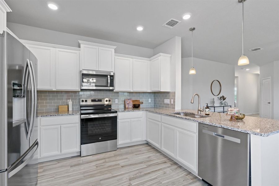 Kitchen featuring appliances with stainless steel finishes, white cabinetry, tasteful backsplash, and recessed lighting