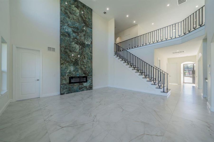 Unfurnished living room featuring a high ceiling, light marble finish flooring, arched walkways, and stairway Unfurnished living room featuring a high ceiling, light marble finish flooring, arched walkways, and stairway