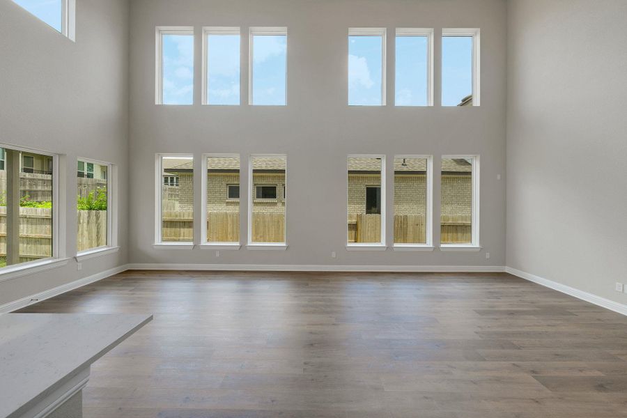 Unfurnished living room with healthy amount of natural light, a towering ceiling, and wood finished floors Unfurnished living room with healthy amount of natural light, a towering ceiling, and wood finished floors