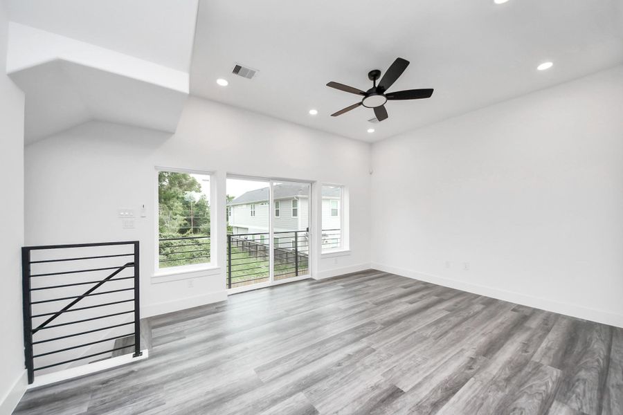 This spacious, modern living area features sleek vinyl flooring, recessed lighting, and a ceiling fan. Large windows and a sliding door provide ample natural light and access to a balcony, enhancing the open, airy ambiance. This spacious, modern living area features sleek vinyl flooring, recessed lighting, and a ceiling fan. Large windows and a sliding door provide ample natural light and access to a balcony, enhancing the open, airy ambiance.