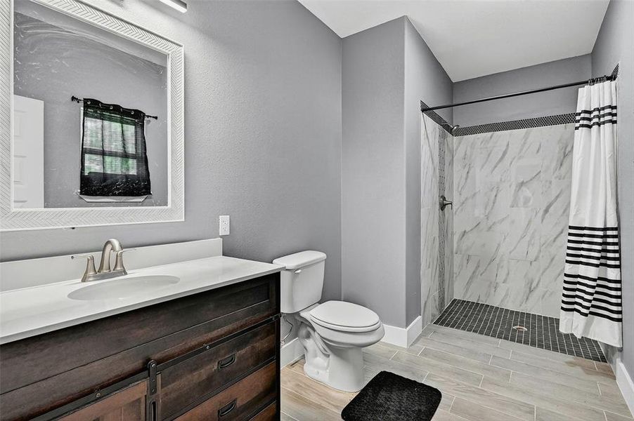 Full bath featuring curtained shower, vanity, and wood tiled floors Full bath featuring curtained shower, vanity, and wood tiled floors