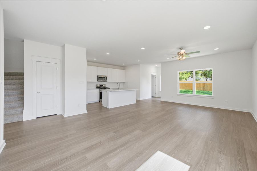 Unfurnished living room with stairway, recessed lighting, light wood-type flooring, and a ceiling fan Unfurnished living room with stairway, recessed lighting, light wood-type flooring, and a ceiling fan