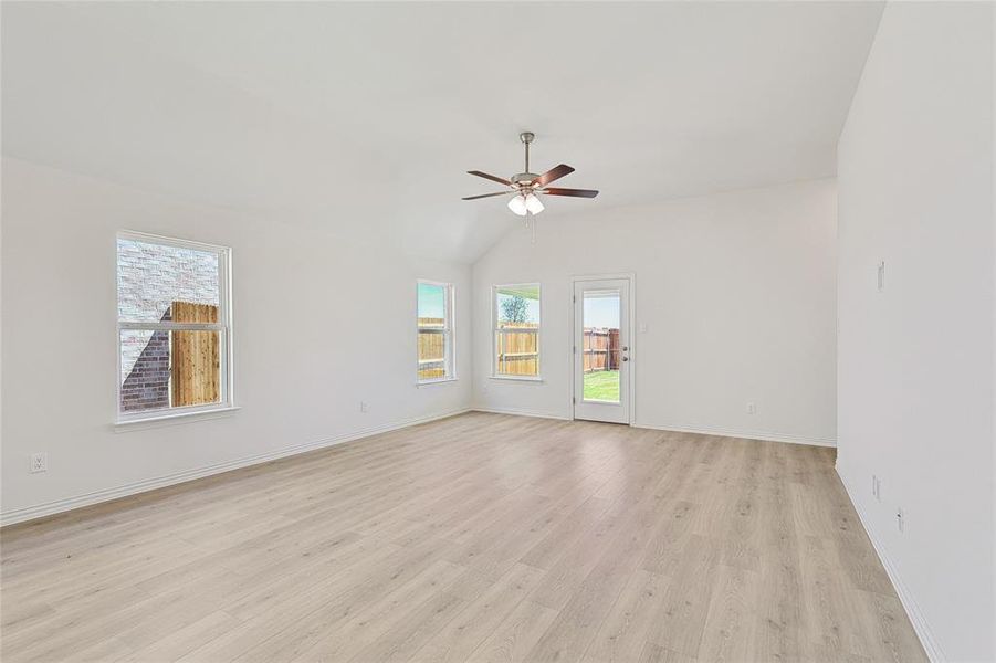 Empty room featuring lofted ceiling, light hardwood / wood-style flooring, and ceiling fan