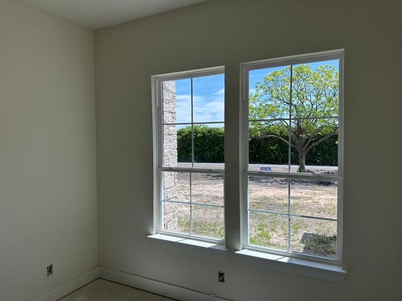 Double-hung windows with white frames and grid patterns, featuring a stone exterior finish