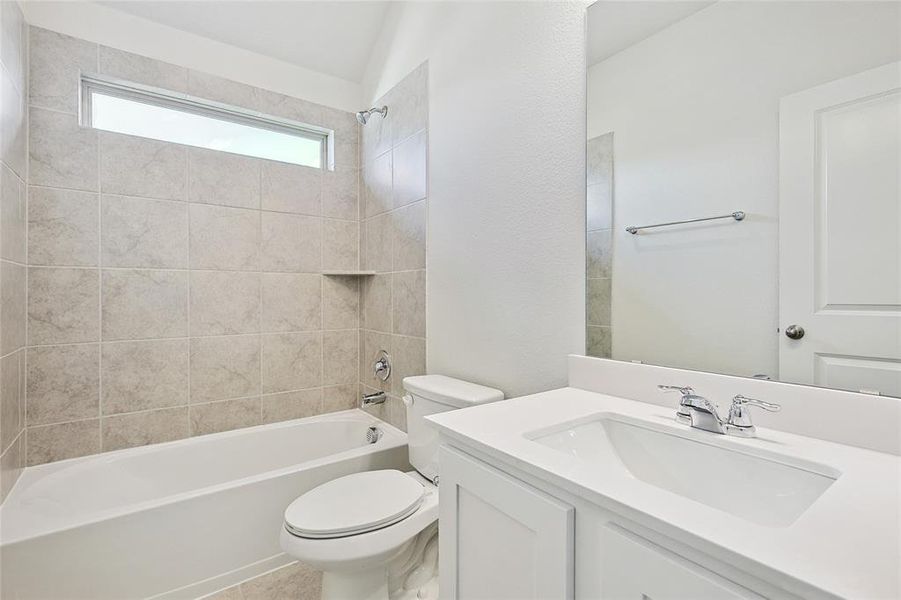 Full bathroom featuring tiled shower / bath combo, toilet, and vanity