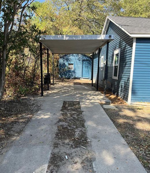 Covered carport structure beside a blue-sided residence