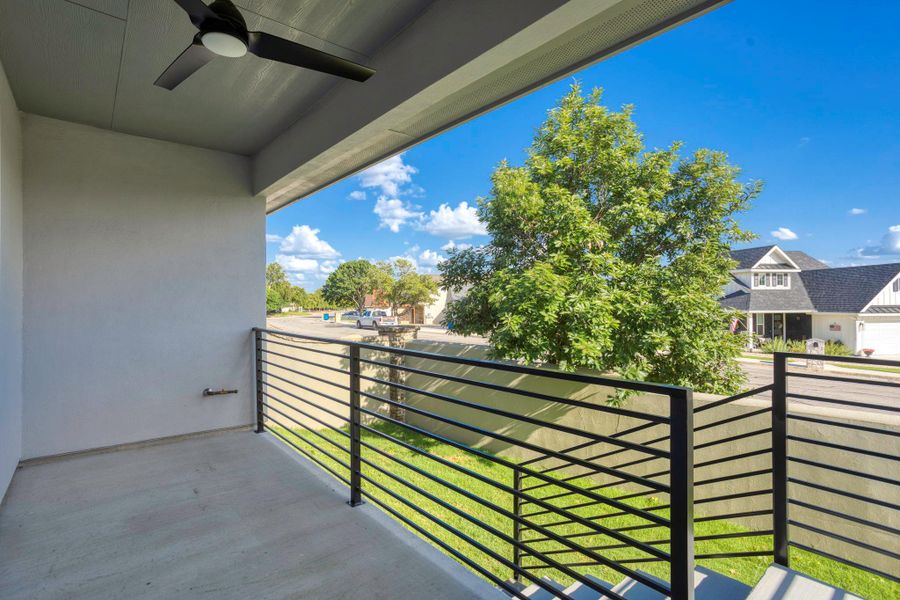 Outdoor balcony featuring a concrete floor, a contemporary ceiling fan, and black horizontal metal railings Outdoor balcony featuring a concrete floor, a contemporary ceiling fan, and black horizontal metal railings