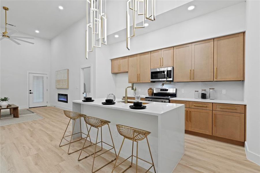 Kitchen with appliances with stainless steel finishes, a towering ceiling, a sink, a breakfast bar, and light wood-style flooring Kitchen with appliances with stainless steel finishes, a towering ceiling, a sink, a breakfast bar, and light wood-style flooring