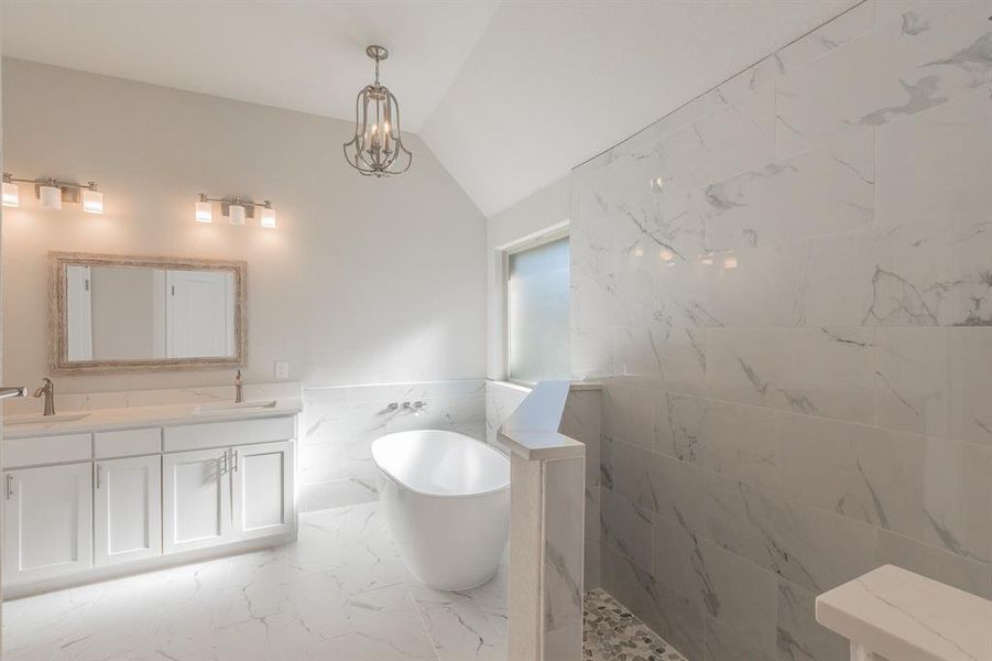 Bathroom with lofted ceiling, a bathtub, vanity, and tile walls