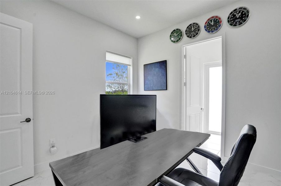 White interior walls, recessed ceiling lighting, light-toned flooring, and a white interior door with dark hardware