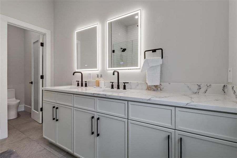 Dual illuminated vanity mirrors elevate a sophisticated primary bathroom with ample counter space.