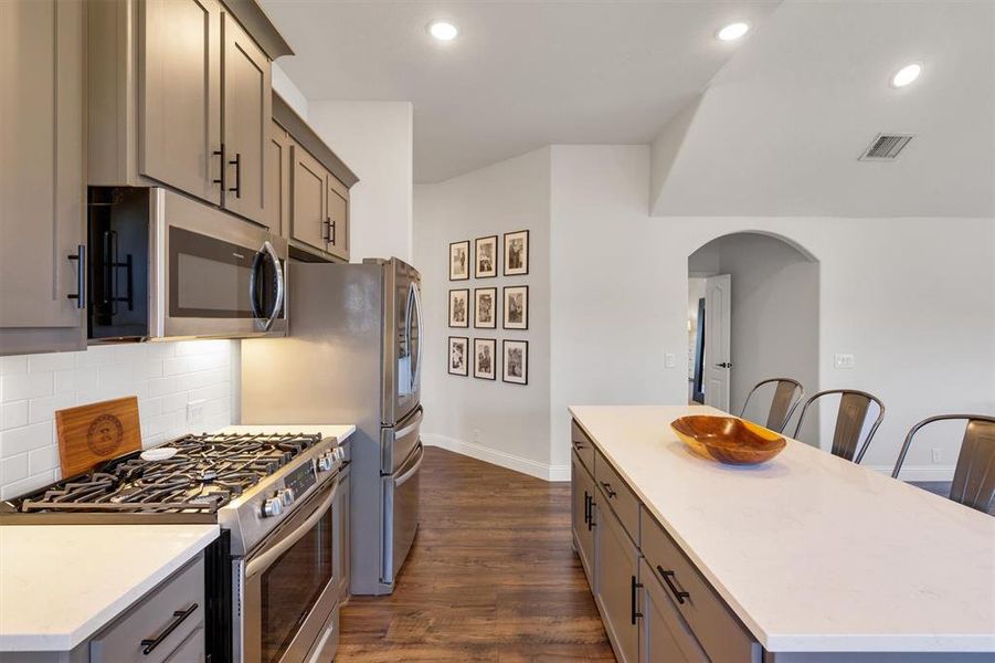 Kitchen featuring gray cabinets, a center island, dark hardwood / wood-style floors, and appliances with stainless steel finishes