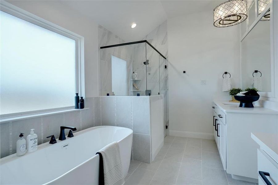 Bathroom featuring vanity, a freestanding tub, a marble finish shower, and light tile patterned floors