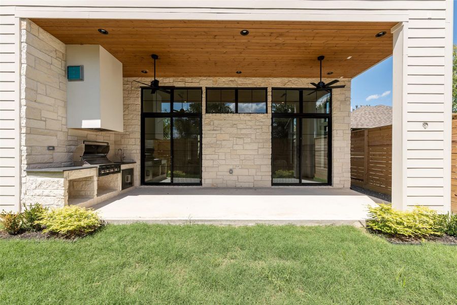 The covered rear patio extends the living experience outdoors, with a built in grill, tongue and groove ceiling and expansive dual sliding glass door systems creating a seamless connection back into the home. The covered rear patio extends the living experience outdoors, with a built in grill, tongue and groove ceiling and expansive dual sliding glass door systems creating a seamless connection back into the home.