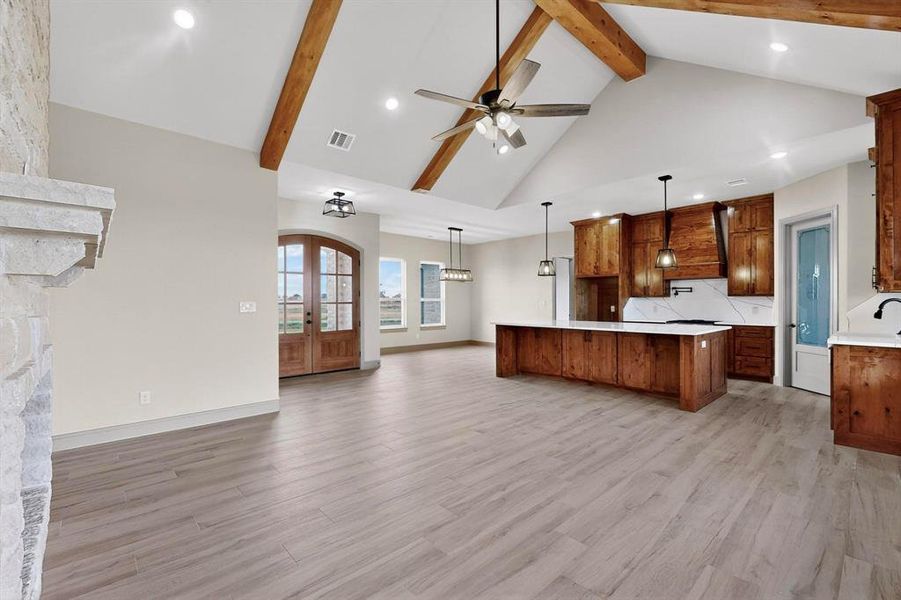 Kitchen featuring french doors, open floor plan, high vaulted ceiling, light wood-style floors, and decorative light fixtures Kitchen featuring french doors, open floor plan, high vaulted ceiling, light wood-style floors, and decorative light fixtures