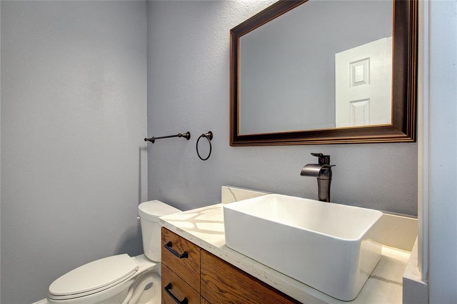 Half bathroom featuring toilet and vanity downstairs near the office