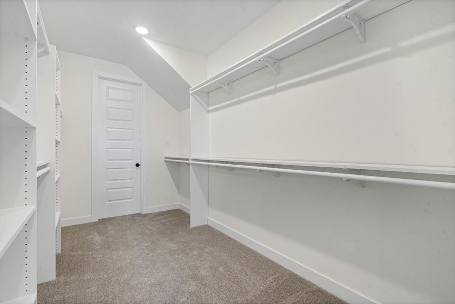 Walk-in closet featuring built-in shelving, dual hanging rods, recessed lighting, and soft carpet flooring Walk-in closet featuring built-in shelving, dual hanging rods, recessed lighting, and soft carpet flooring