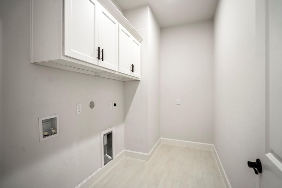 Large laundry room with built in cabinetry and ample storage space.