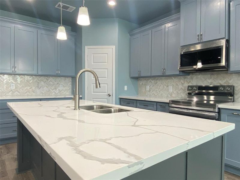 A contemporary kitchen features an island with a sink, sleek cabinetry, and stainless steel appliances. A contemporary kitchen features an island with a sink, sleek cabinetry, and stainless steel appliances.
