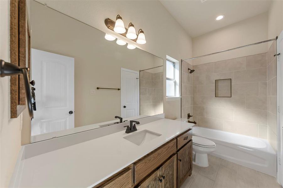 Full bathroom featuring toilet, vanity, tiled shower / bath combo, and tile patterned flooring