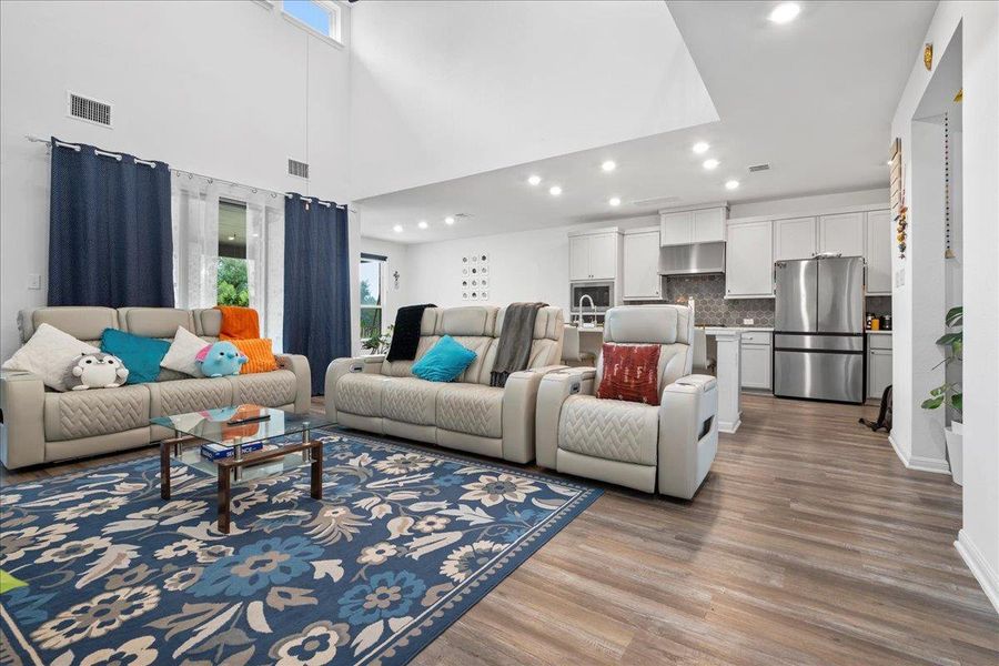 Living area with light wood-style floors, recessed lighting, and a high ceiling