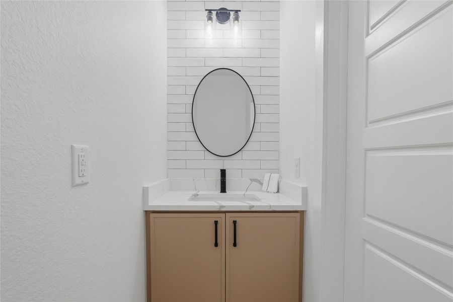 The half bathroom on the first floor includes a quartz countertop, black fixtures, and built-in shelving for décor or linens.