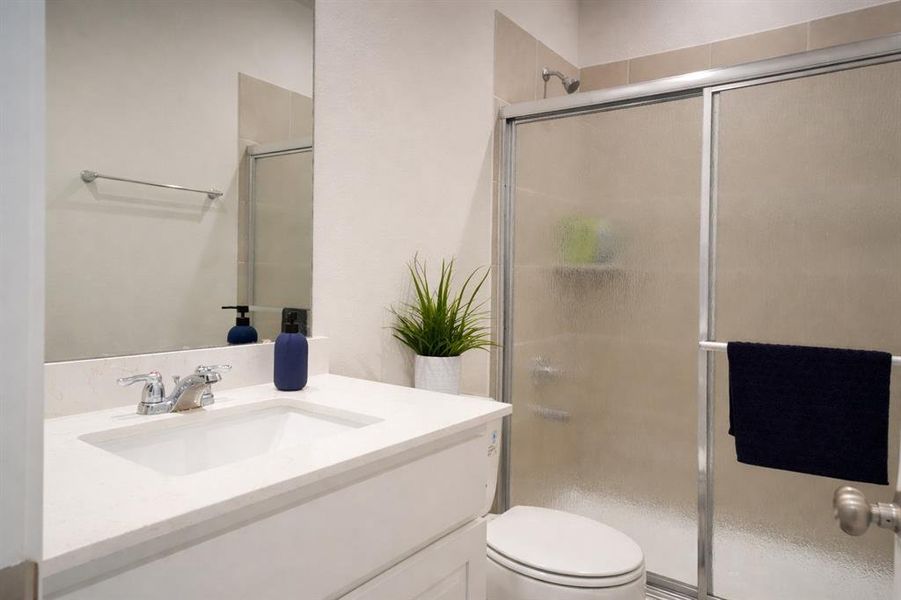 Bathroom featuring a vanity with an integrated sink, polished chrome faucet, framed mirror, and a shower with a sliding frosted glass door
