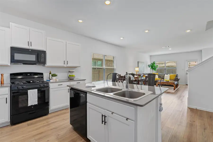 Kitchen with black appliances, white cabinetry, plenty of natural light, light wood finished floors, and recessed lighting