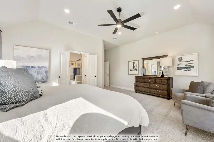 Spacious master bedroom with ceiling fan, carpet flooring, wood dresser, and ensuite bathroom doorway