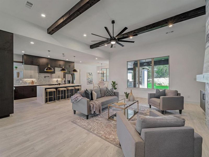 Living room featuring beam ceiling, light wood finished floors, a ceiling fan, recessed lighting, and a fireplace