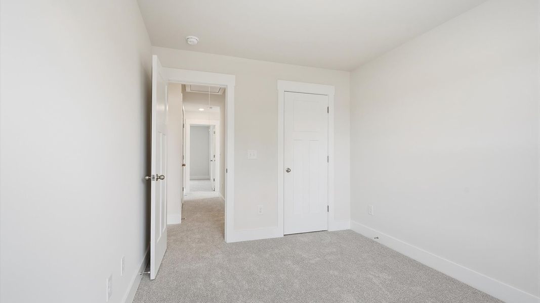 Notable secondary bedroom offering cozy carpeted flooring and a stylish walk-in closet at the Clarke Townes community