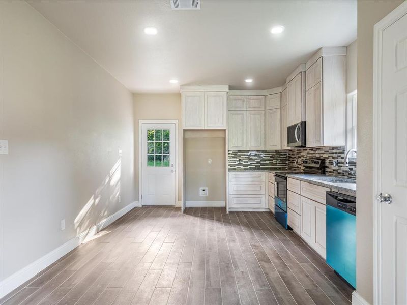 Kitchen featuring dishwasher, stainless steel microwave, electric range, wood finished floors, and decorative backsplash Kitchen featuring dishwasher, stainless steel microwave, electric range, wood finished floors, and decorative backsplash