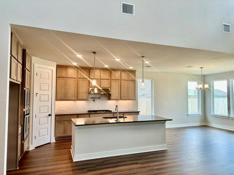An open floorplan seamlessly connects the kitchen and living areas, highlighted by a practical kitchen island and rich hardwood flooring. An open floorplan seamlessly connects the kitchen and living areas, highlighted by a practical kitchen island and rich hardwood flooring.