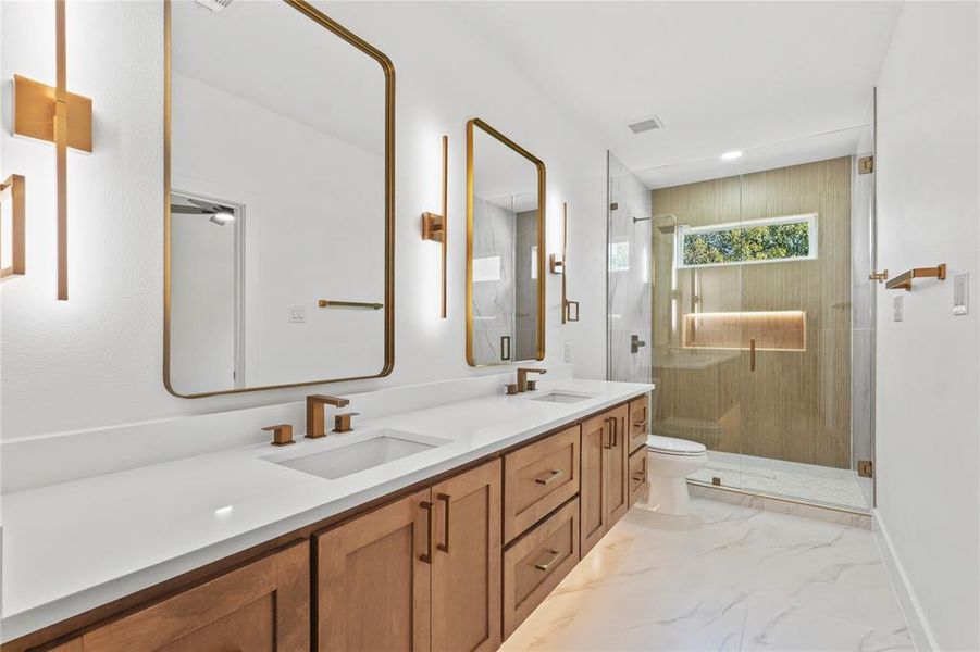 Bathroom with double vanity, a marble finish shower, light marble finish floors, and recessed lighting