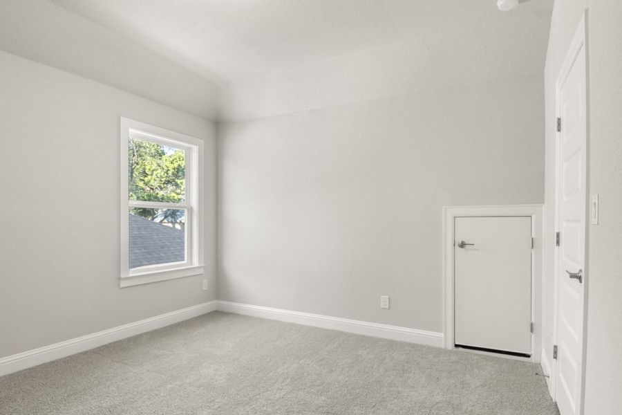 Image of a bedroom with grey carpeting and flooring and a window in the corner in room