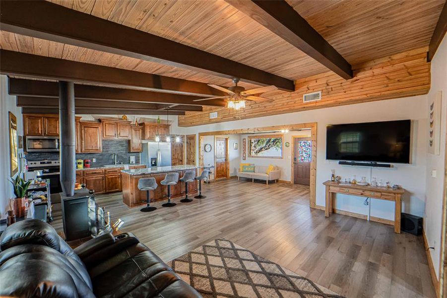 Living area featuring ceiling fan, light wood-type flooring, and beamed ceiling Living area featuring ceiling fan, light wood-type flooring, and beamed ceiling