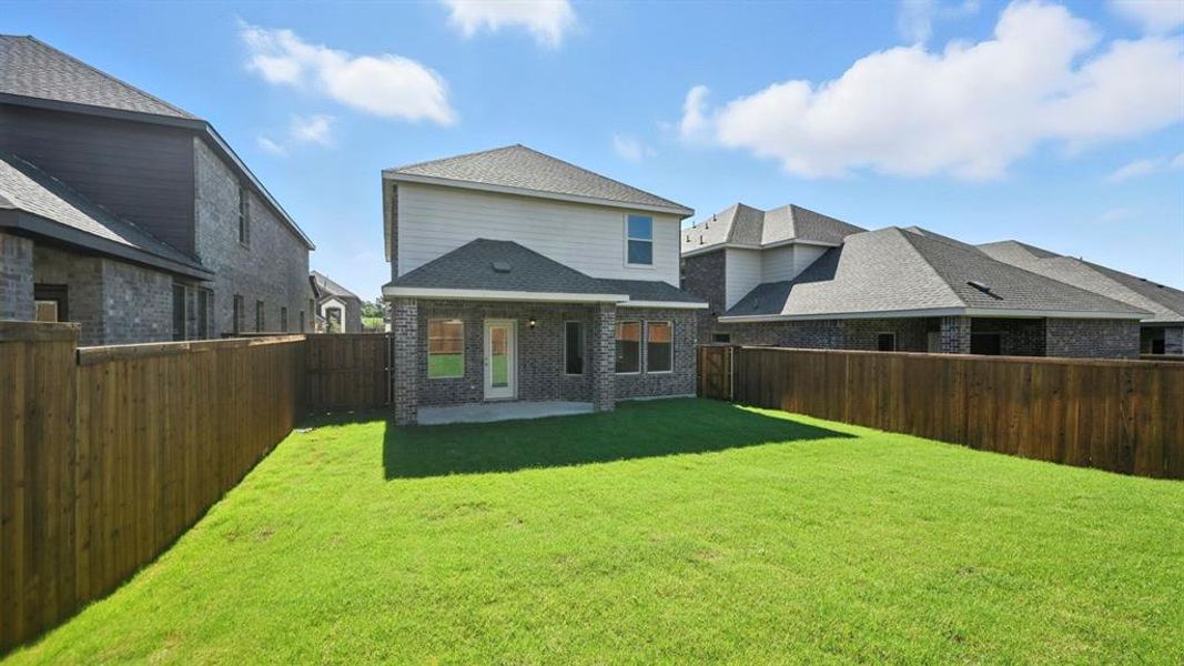 Rear view of house with a shingled roof, brick siding, a patio, and a fenced backyard