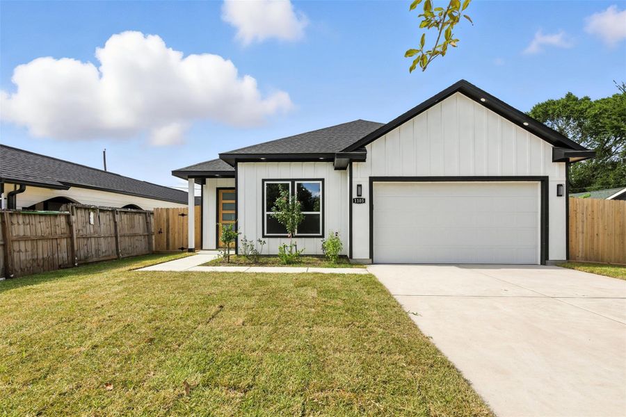 This is a modern single-story home with a clean, black-and-white exterior. It features a spacious front yard with a simple driveway leading to a two-car garage. The yard is enclosed by a wooden fence, offering a touch of privacy.