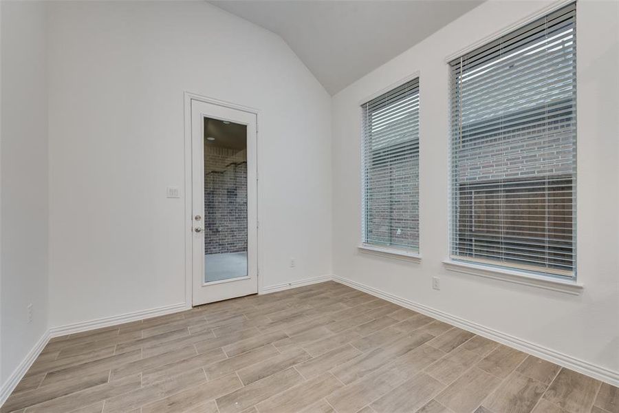 Unfurnished room featuring vaulted ceiling and light hardwood / wood-style flooring