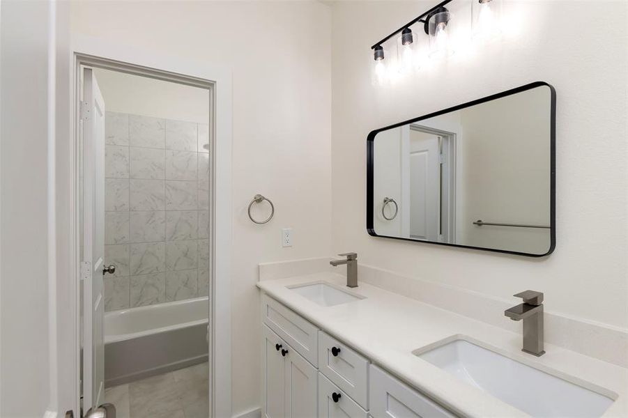 Full bathroom featuring double vanity, shower / tub combination, and a sink