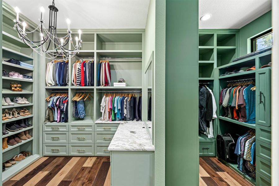 Expansive built-in walk-in closet with custom cabinetry, elegant lighting, and boutique-style organization Expansive built-in walk-in closet with custom cabinetry, elegant lighting, and boutique-style organization