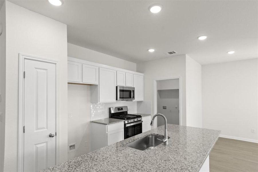 Kitchen with a sink, visible vents, white cabinetry, appliances with stainless steel finishes, and tasteful backsplash