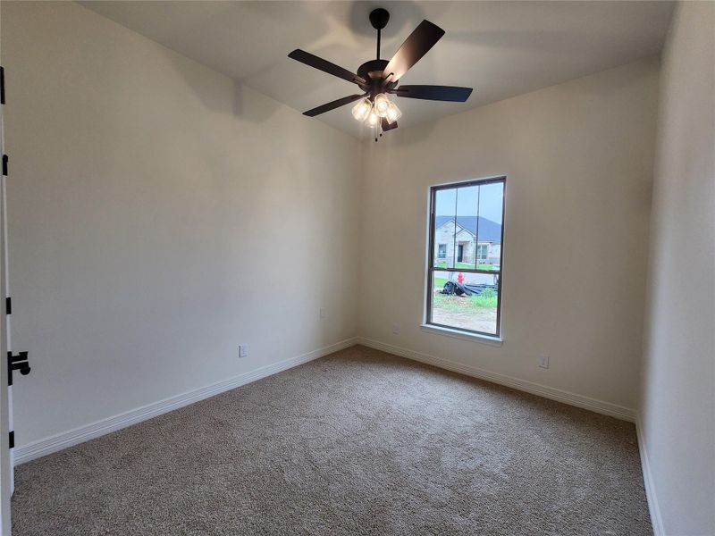 Carpeted room with vaulted ceiling and a ceiling fan with integrated lighting