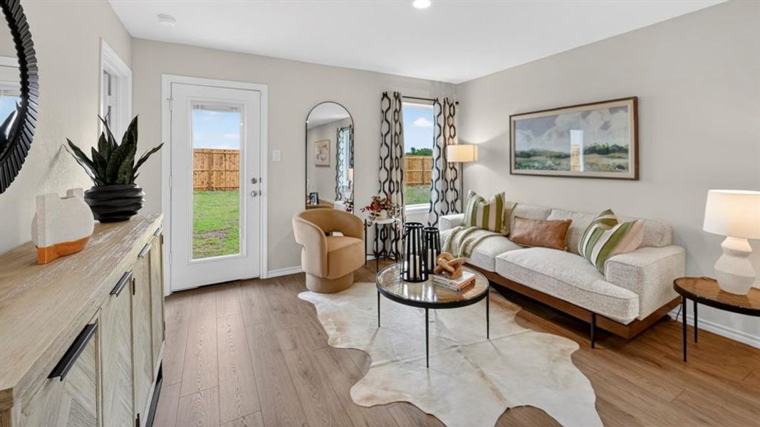 Spacious living area featuring wood-finish flooring, light-toned walls, and a glass-paneled exterior door Spacious living area featuring wood-finish flooring, light-toned walls, and a glass-paneled exterior door
