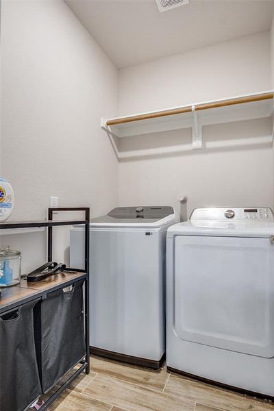 Laundry room with wood tiled floors and separate washer and dryer